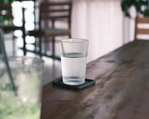 A freshly poured tall glass of clear drinking water standing on a modern wooden breakfast counter in soft daylight