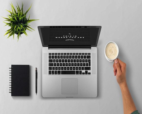 A small styled desktop desk with a clear notebook and an artisanal coffee cup over clean background
